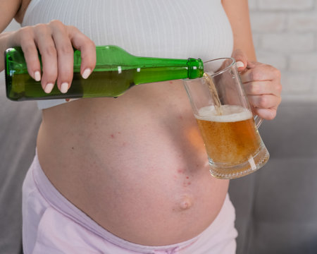 Faceless pregnant woman pouring beer into a glassの写真素材
