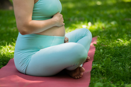 Close up belly of pregnant woman doing yoga outdoorsの写真素材