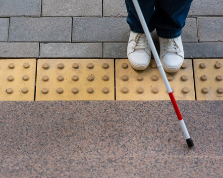 Blind woman walking outdoors using a tactile caneの写真素材