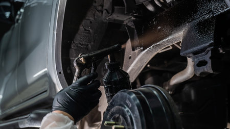 The master sprays an anti-corrosion compound on the bottom of the car