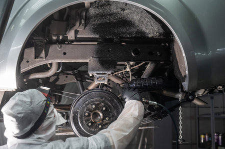 The master sprays an anti-corrosion compound on the bottom of the car
