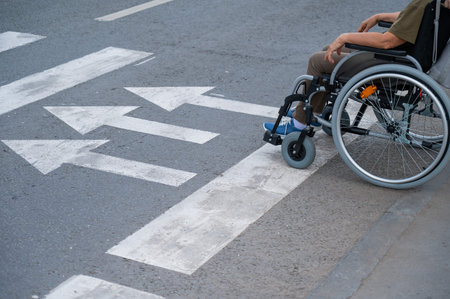 An elderly woman in a wheelchair is about to cross the road at a pedestrian crossingの写真素材
