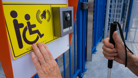 Close-up of the hands of a blind elderly woman reading a text in braille. Button for calling help for people with disabilitiesの写真素材