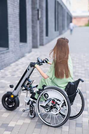 A woman in a wheelchair with an assistive device for manual control. Electric handbikeの写真素材