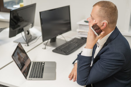 Caucasian man with a hearing aid talking on the phone on speakerphone