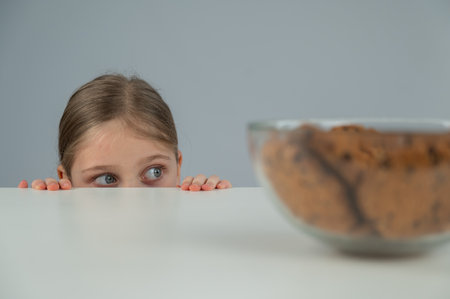 A little girl tries to steal cookies from the tableの写真素材
