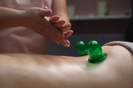 A woman undergoes an anti-cellulite massage procedure using a vacuum jar. Close-up of the lower backの写真素材