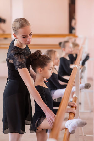 Caucasian woman teaches little girls ballet at the barre. Vertical photoの写真素材