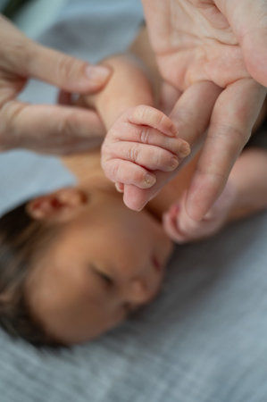 A newborn boy holds his mothers finger. Close-up of handsの写真素材