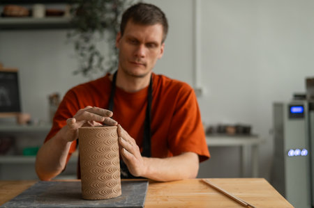 Potter sculpts a patterned cylinder from clayの写真素材