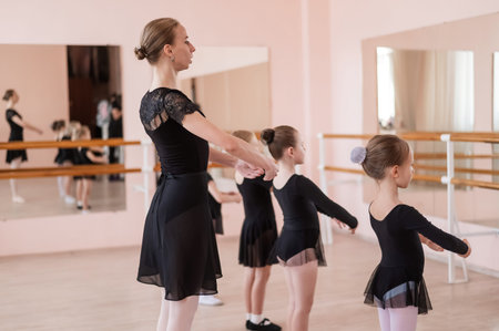 Childrens ballet school. Caucasian woman teaching ballet to little girlsの写真素材