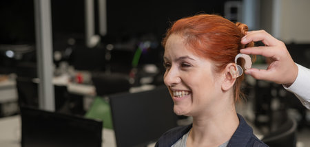 Man putting hearing aid on Caucasian red-haired womanの写真素材