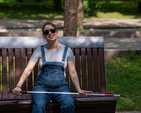 Red-haired woman sitting on a bench outdoorsの写真素材