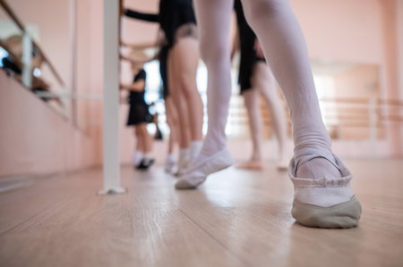 Little girls practice ballet at the barre. Close-up of young ballerinas feetの写真素材