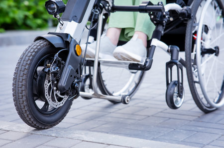 A faceless woman in a wheelchair with an assistive device for manual control. Electric handbikeの写真素材