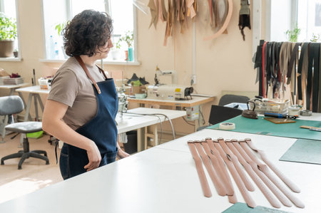 Caucasian woman makes belts from genuine leather in a workshopの写真素材