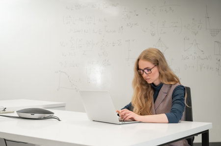 Caucasian woman scientist typing on laptop. White board with formulasの写真素材