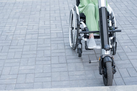 A faceless woman in a wheelchair with an assistive device for manual control. Electric handbikeの写真素材