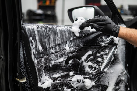 A man cleans the interior of a car with foam and a brush. Clean the door trimの写真素材