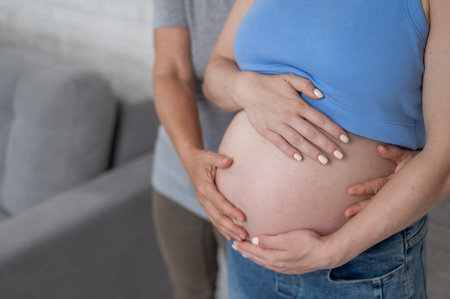 An elderly woman touches the belly of her pregnant daughter. Close-upの写真素材