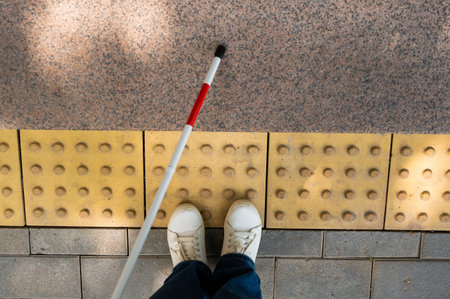Close-up of female foot, walking stick and tactile tilesの写真素材