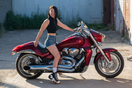 Brunette woman in shorts on a red motorcycleの写真素材