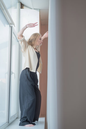 Caucasian woman dancing modern dance on the windowsill. Vertical photoの写真素材