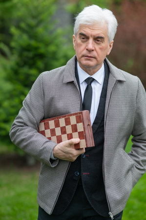 Elderly Caucasian man holding chess outdoors. Vertical photoの写真素材