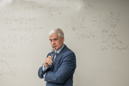Mature man stands at a white board with written formulasの写真素材