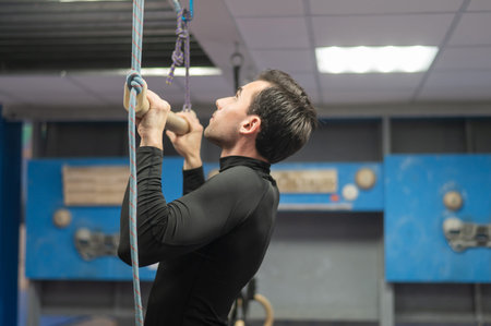 Caucasian man doing pull-ups on trapeze. Warm-up before the climbing wall
