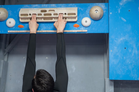 Caucasian man training his fingers on a wooden fingerboard in a rock climbing gymの写真素材