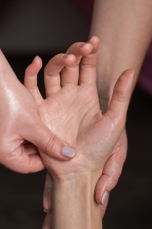 The masseuse massages the clients palms. Close-up of hands during a spa treatment. Vertical photoの写真素材