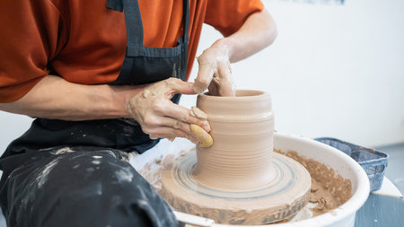 Close-up of a potters hands making a ceramic vase on a potters wheelの写真素材