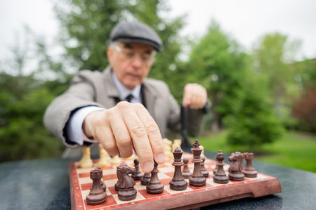 Elderly Caucasian man playing chess outdoors