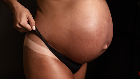 Pregnant woman pulls back her panties showing instant tanの写真素材
