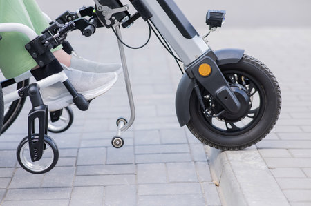 A faceless woman in a wheelchair with an assistive device for manual control. Electric handbikeの写真素材