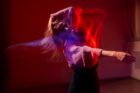 A young woman dances contemporary dances in blue and red light. Long exposure photo