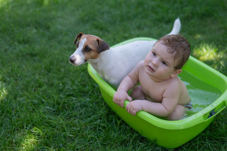 Cute boy bathes in a basin with a Jack Russell terrier dog outdoors in the summer