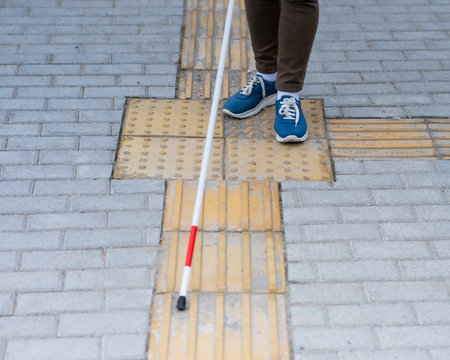 Close-up of a womans legs with a cane near a tactile tileの写真素材