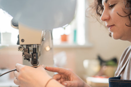 A woman tanner sews a leather belt on a sewing machine