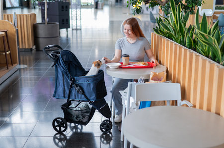 Caucasian woman having lunch in a cafe with her Jack Russell terrier dog in a stroller
