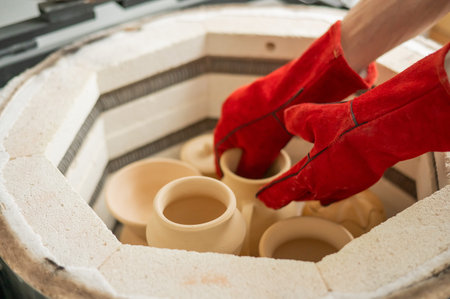 Close-up of male hands taking ceramics into a special kiln