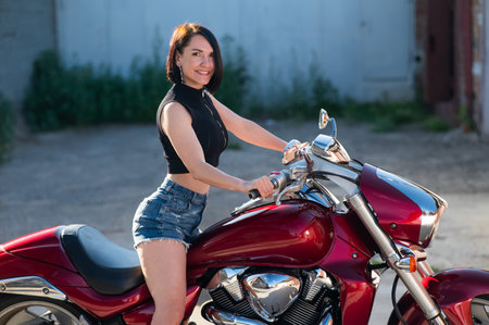 Brunette woman in shorts on a red motorcycleの写真素材