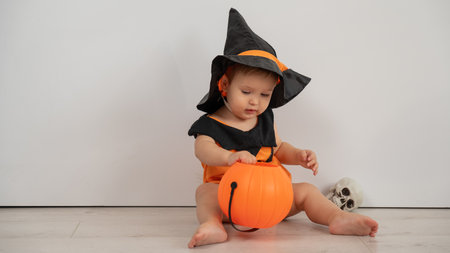 Cute boy in halloween pumpkin costume holding candy basket on white backgroundの写真素材