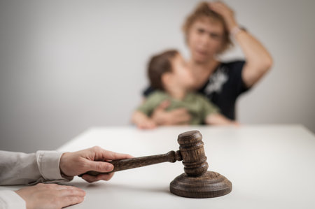 A judge hits a gavel against the backdrop of an elderly woman holding a childの写真素材