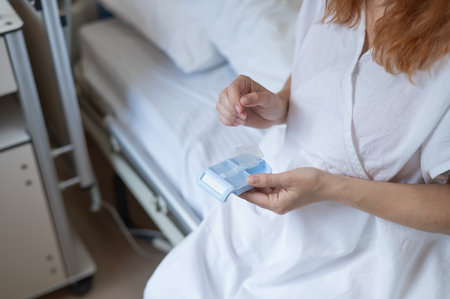 Close up of hands. Woman holding pillbox in hospitalの写真素材
