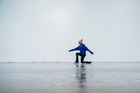 Caucasian woman in a blue sweater is skating on a frozen lake. The figure skater performs the programの写真素材