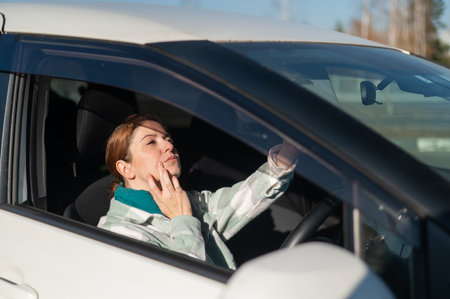 Caucasian woman sitting behind the wheel and looking in the mirrorの写真素材