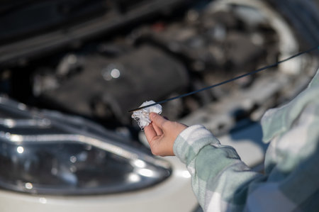 Close up of hands of female driver checking oil level in car engine