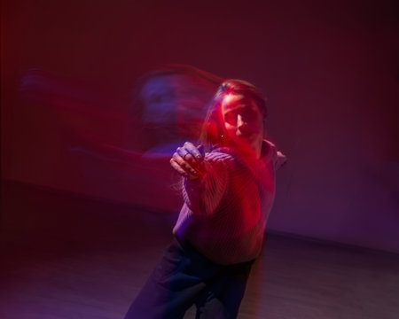 A young woman dances contemporary dances in blue and red light. Long exposure photoの写真素材